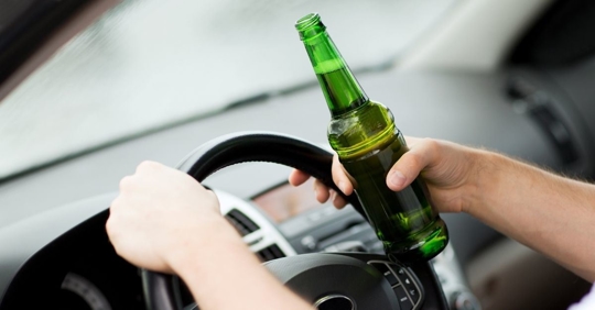 person holding a beer bottle while driving
