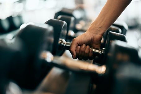 Close-up of a female hand picking up a heavy dumbbell