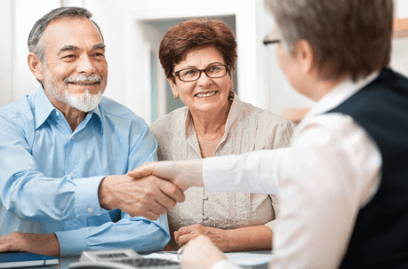 An elderly couple meeting with a lawyer and shaking her hand