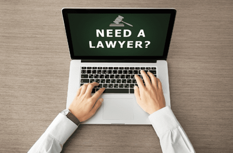 Man typing "need a lawyer" on a laptop