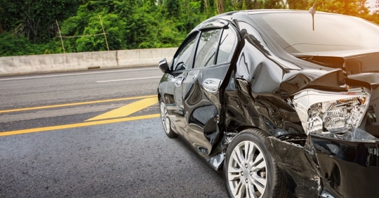 side view of a black car with significant side damage